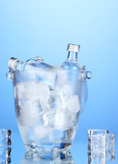 Minibar bottles in bucket with ice cubes,  on blue background