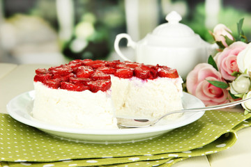 Cheesecake with fresh strawberry on white plate on wooden table
