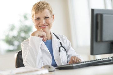 Confident Female Doctor Sitting At Computer Desk