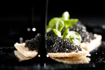 Outdoor kussens Sandwiches with black caviar on black background © Natalia Lisovskaya