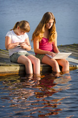 Fototapeta na wymiar Girls internet surfing in lake scenery
