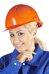 Fröhliche Handwerkerin mit Blaumann und rotem Bauhelm