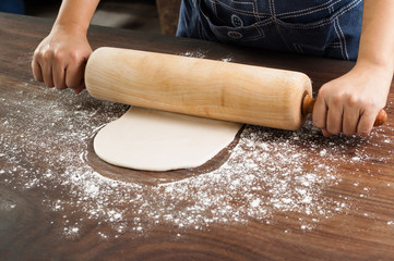 Hands with rolling pin and pie dough.