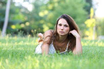 young brunette beautiful woman lying on meadow. outdoor portrait