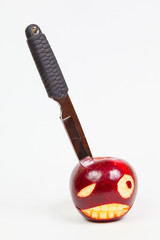 angry face is carved on an apple and a knife
