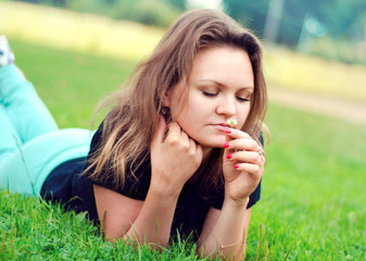 Girl smelling a flower lying on the grass