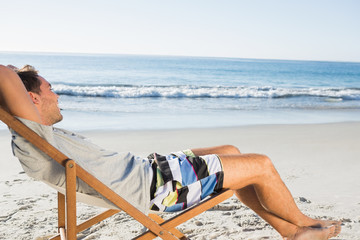 Handsome man lying on his deck chair admiring sea