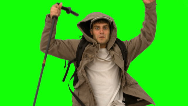 Man with a hiking stick jumping on green screen