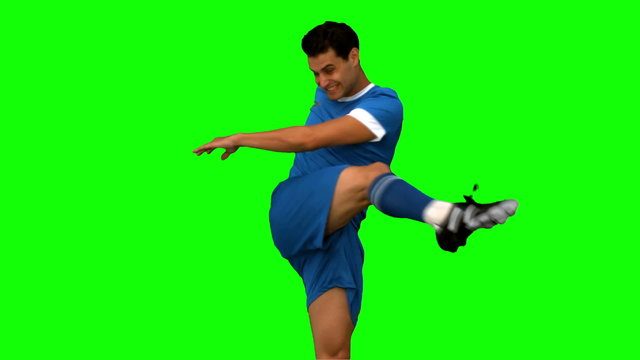 Football player kicking a football on green screen
