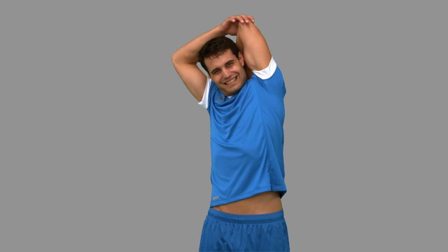 Football player stretching arms on grey screen