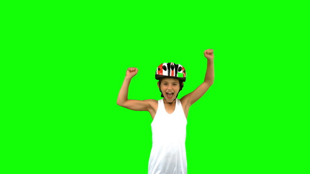Cute girl wearing a bike helmet and raising arms on green screen