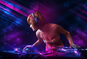 Young DJ playing on turntables with color light effects