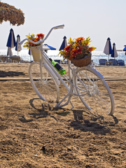bicycle parked on a beach next to the umbrellas