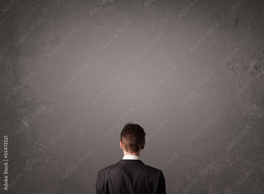 Wall mural Businessman standing in front of an empty wall