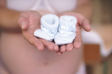 schwangere Frau mit kleinen Babyschuhen