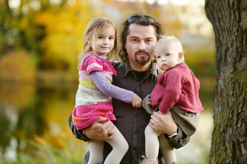 Fototapeta na wymiar Young father and his daughters at fall
