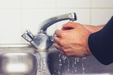 Man washing his hands in kirchen sink