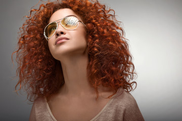 Red Hair. Beautiful Woman with Curly Long Hair and Sunglases