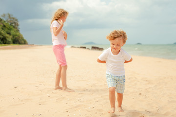 two happy kids playing at the beach in the day time