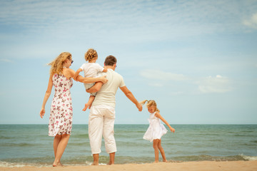 Happy family standing at the beach in the day time