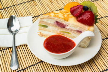 Crepes cake with orange, kiwi and strawberry sauce