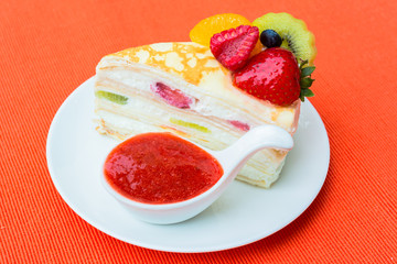 Crepes cake with orange, kiwi and strawberry sauce
