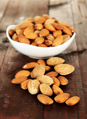 Almond in bowl, on wooden background