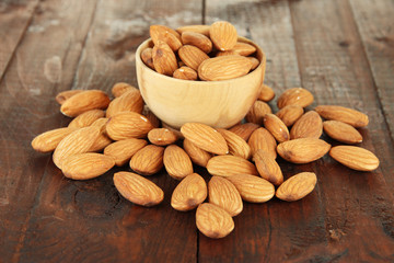 Almond in wooden bowl, on wooden background