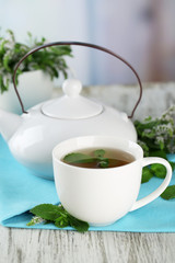 Teapot and cup of herbal tea with fresh mint flowers