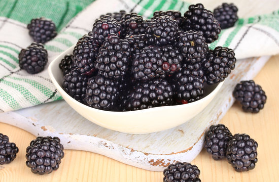 Sweet blackberry in bowl on wooden table