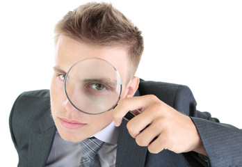 Young businessman looking through magnifying glass isolated