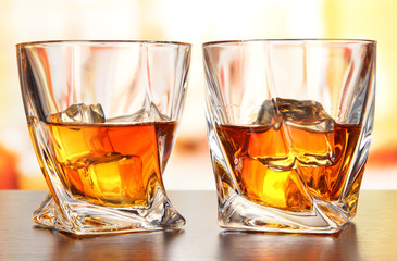 Glasses of whiskey, on bright background