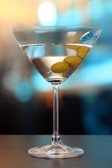 Martini with green olives on table in bar