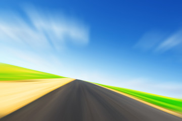 Asphalt road in motion blur and blue sky.