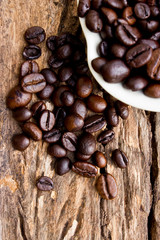 Coffee beans in white cup on wooden background.