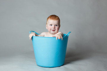 laughing baby in a blue bucket