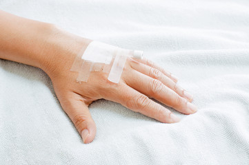 Hand of man with drip in hospital bed