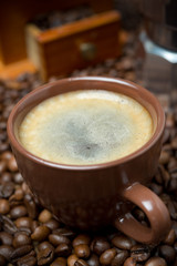 cup of black coffee with froth on the background of coffee beans