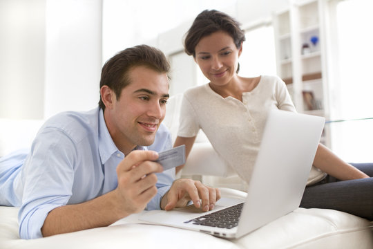 Couple using credit card to shop online, on couch indoor