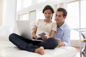 Couple using credit card to shop online indoor