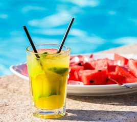 Lime cocktail in front of plate filled with red melon