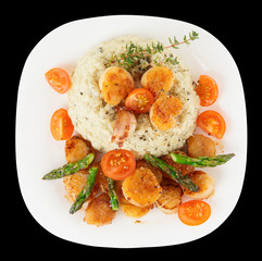 Risotto with pan seared sea scallops isolated on black