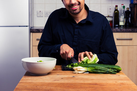 Happy man chopping vegetables