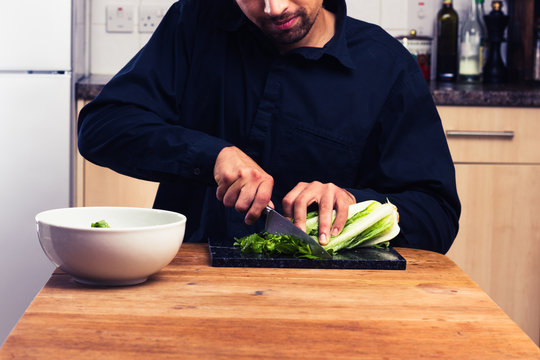 Man at kitchen table chopping lettuce
