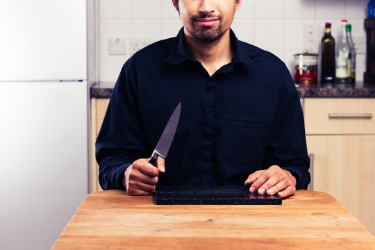 Man in kitchen with knife and chopping board