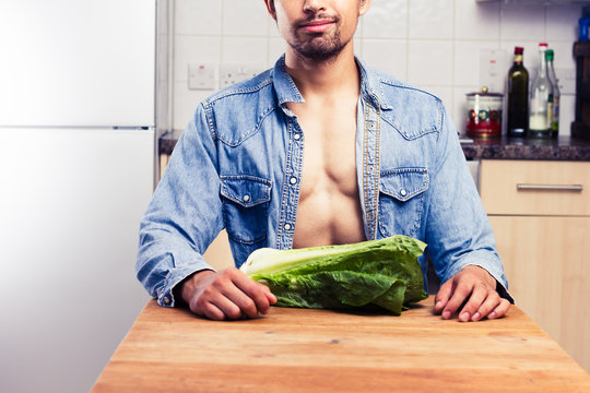 Sexy man in kitchen with lettuce