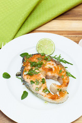 Grilled salmon steak on white plate with spices