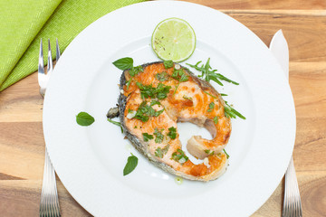 Grilled salmon steak on white plate with spices
