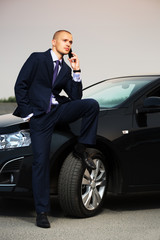 Young businessman calling on the phone at the car
