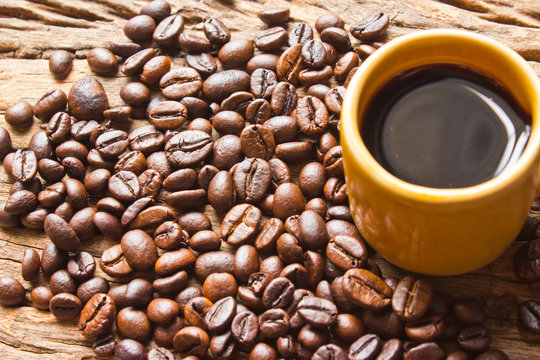 Cup of black coffee and coffee beans on  wooden background.